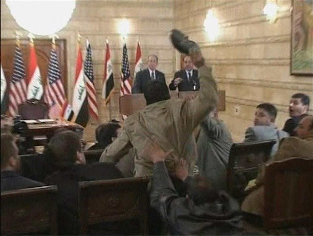 In this image from APTN video, a man, centre throws a shoe at President George W. Bush, background left, during a news conference with Iraq Prime Minister Nouri al-Maliki on Sunday in Baghdad, Iraq. On an Iraq trip shrouded in secrecy and marred by dissent, President George W. Bush on Sunday hailed progress in the war that defines his presidency and got a size-10 reminder of his unpopularity when a man hurled two shoes at him during a news conference.