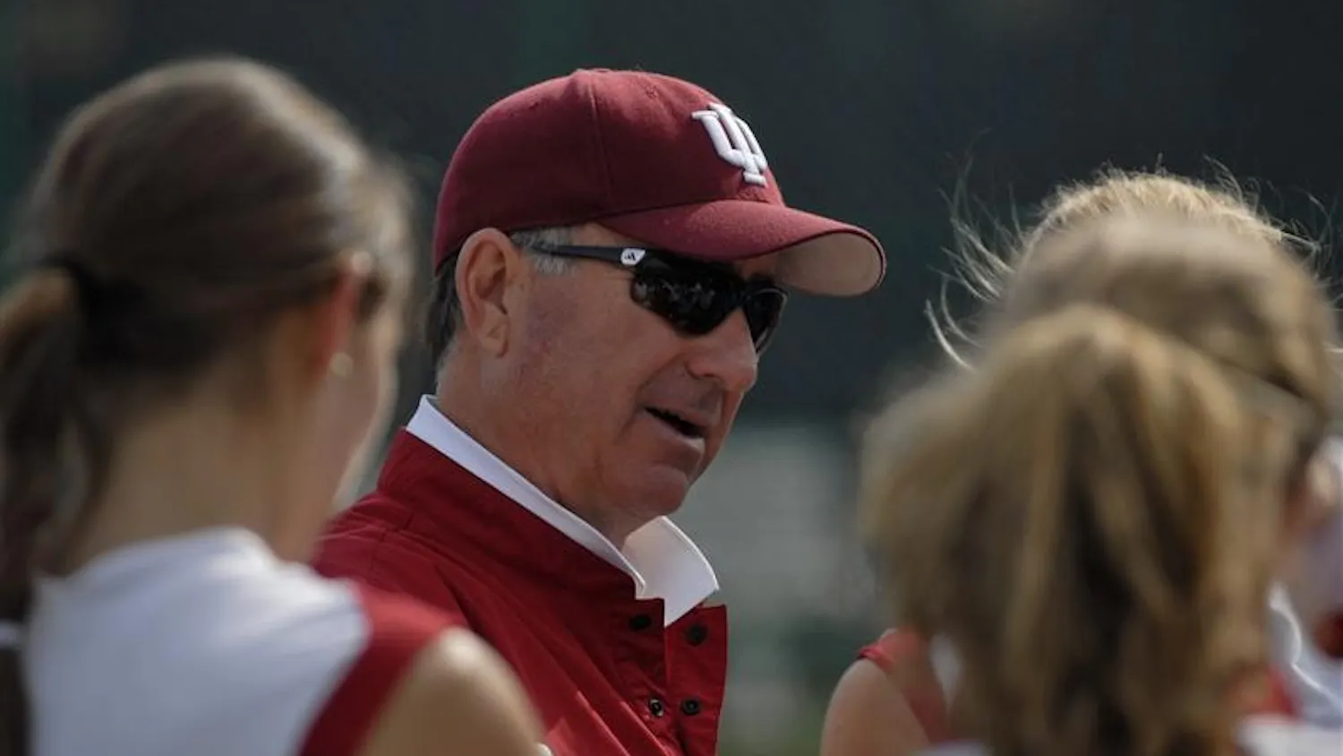 IU women's tennis coach Lin Loring addresses his players during their match against Iowa Saturday afternoon at the outdoor tennis courts. They won their match 4-3.