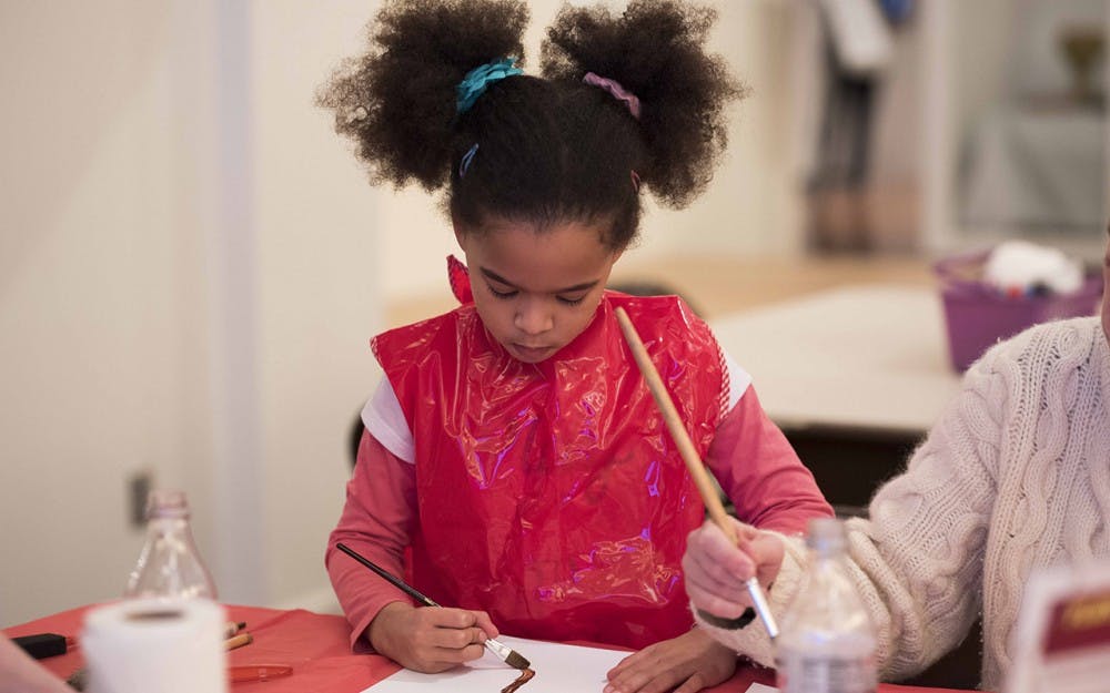 Evelyn Butler and her mother Emily Butler paint cherry blossoms in spirit of Chinese New Year. The art event took place at the Mathers Museum of World Cultures Sunday afternoon. 