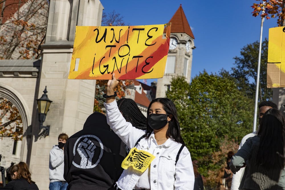 2020年10月16日，小伊芙琳·桑切斯在Sample gate前举行的“Unite to Ignite”集会上抗议。印第安纳大学的学生将于周五投票表决一项法案，该法案可能会增加印第安纳大学学生会的席位，为来自多元文化社区的声音创造更多的代表空间。< / p >