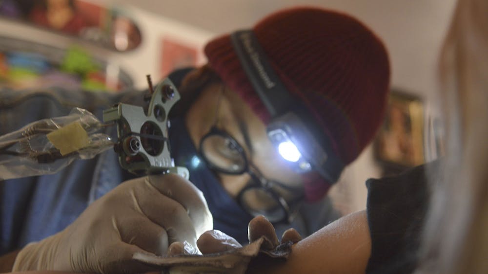 10月28日，Terin正在为一个客户的蛇纹身工作。他在额头上戴了一盏灯，以便更好地看纹身，同时保持工作室的灯光令人赏心悦目。