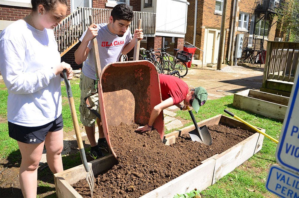 The La Casa Latino Cultural Center staffs make raised garden beds for the kitchen garden to celebrate Earth Day on Friday behind the center. 
