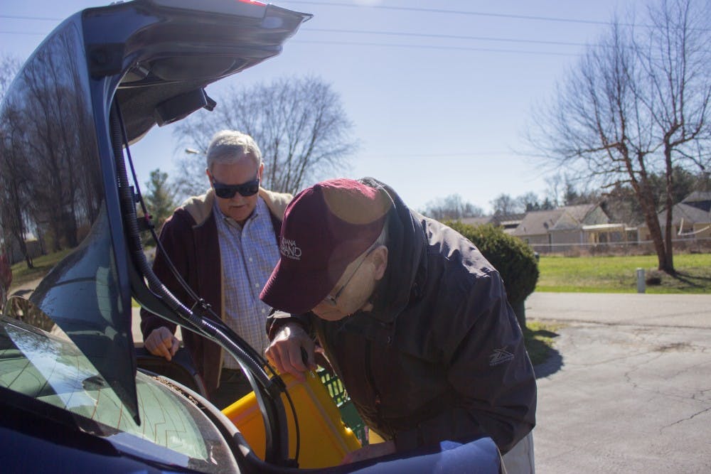 Meals on Wheels volunteers Pat Patterson and Bill Milroy retrieve a hot meal for one of their deliveries. The two men met through the program and now get together once a month to deliver meals to clients.