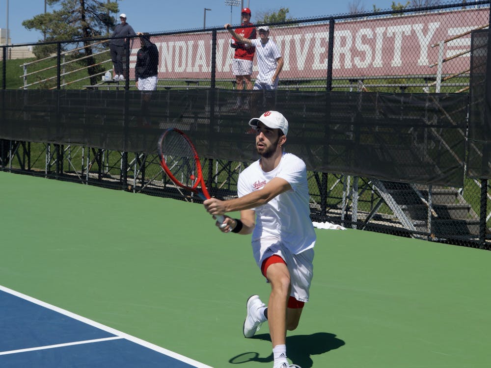 Senior Luka Vukovic kneels for a backhand at the singles match April 2, 2023, at the IU Tennis Courts.