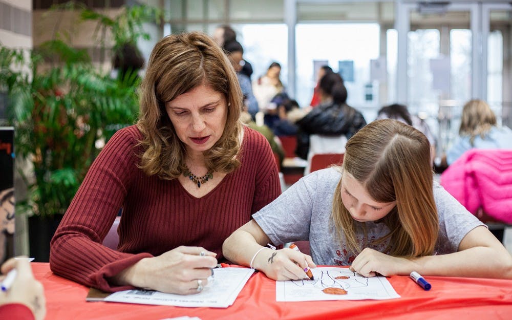 A young&nbsp;girl colors a Martin Luther King Jr. sketch while her mother reads about King at the MLK Birthday Celebration. The community teach-in, for both children and their families, took place&nbsp;Sunday&nbsp;in the IU School of Education. The celebration included coloring activities, a musical performance, an interactive discussion and a celebratory birthday cake.