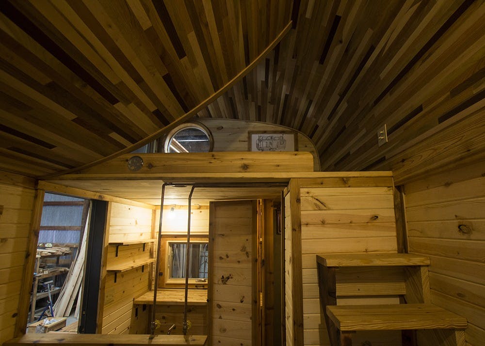 The main interior space of the tiny house holds a tiny stove, tiny sink and regular-sized bathroom. The project was commissioned to be placed on a southern Indiana farm and can be both mobile and permanently set.