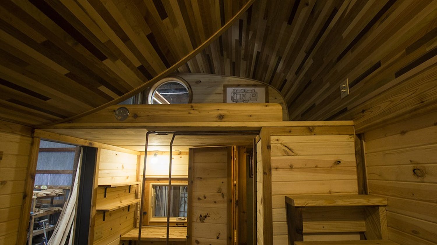 The main interior space of the tiny house holds a tiny stove, tiny sink and regular-sized bathroom. The project was commissioned to be placed on a southern Indiana farm and can be both mobile and permanently set.