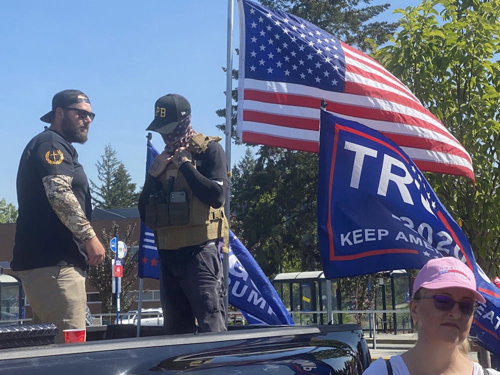 Men wearing symbols of Proud Boys, a violent right-wing extremist group, stand watch as supporters of President Donald Trump kick off a truck caravan near Portland, Oregon.
