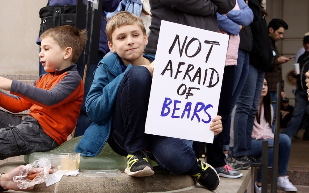 A boy holds a sign referencing a comment made by Betsy Devos, President Trump's pick for education secretary. DeVos said school teachers should be armed to protect children from grizzly bears.