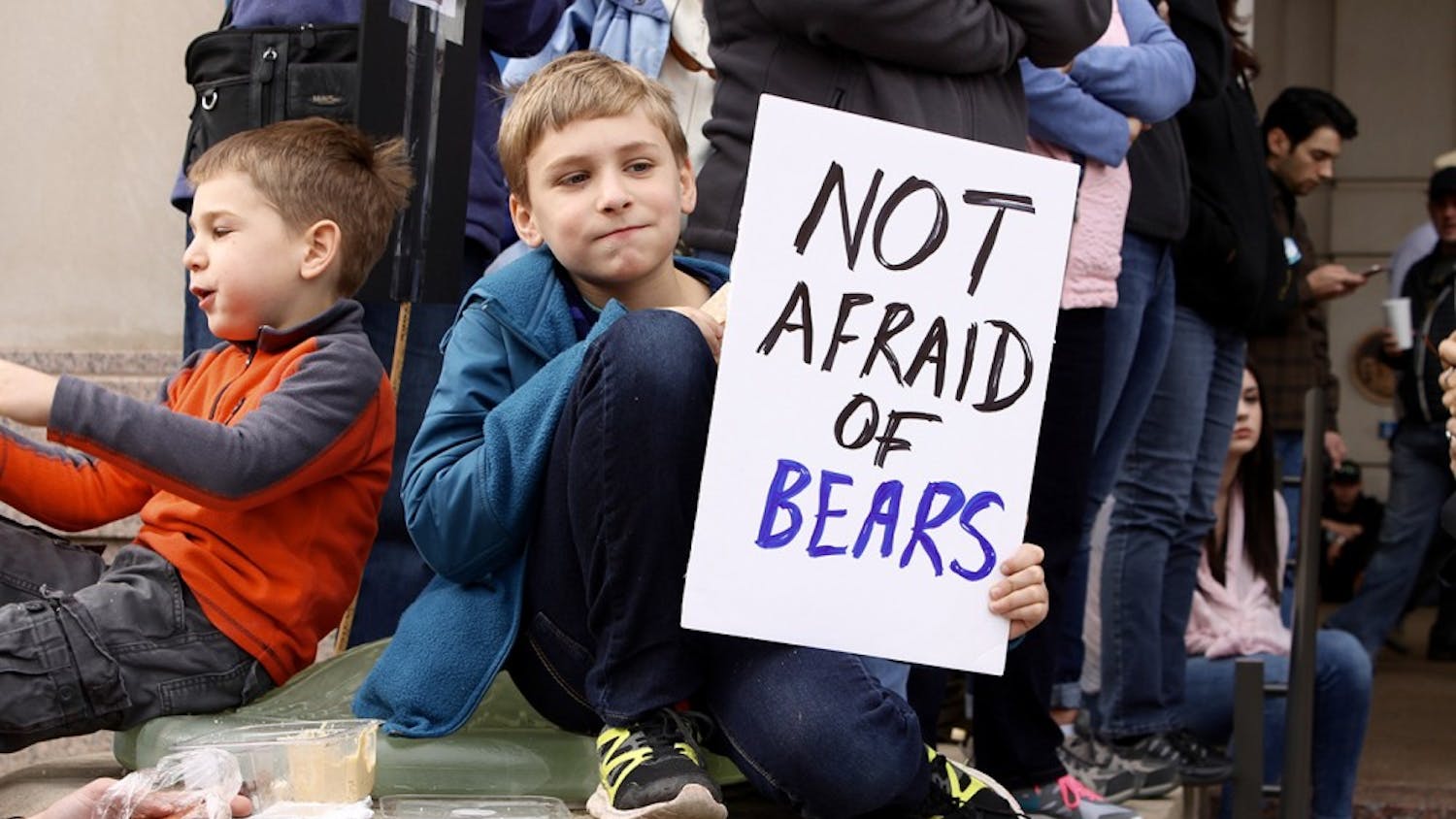 A boy holds a sign referencing a comment made by Betsy Devos, President Trump's pick for education secretary. DeVos said school teachers should be armed to protect children from grizzly bears.
