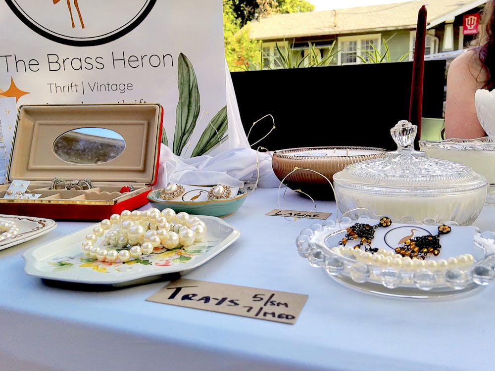 Earrings and glassware with candles are displayed July 14, 2023, at the Elm Coffehouse Summer Pop Up. Brass Heron sells upcycled candles and vintage goods.