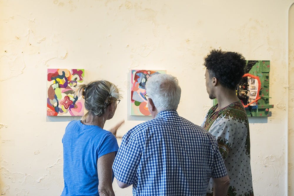 Tina Newberry, an IU painting professor, and Barry Gealt, a retired IU fine arts professor, discuss the works on display at Blueline Gallery with a visitor. The artwork was part of “High Chroma,” an exhibit by Madeline Winter and Mitch Raney, both IU MFA graduates.