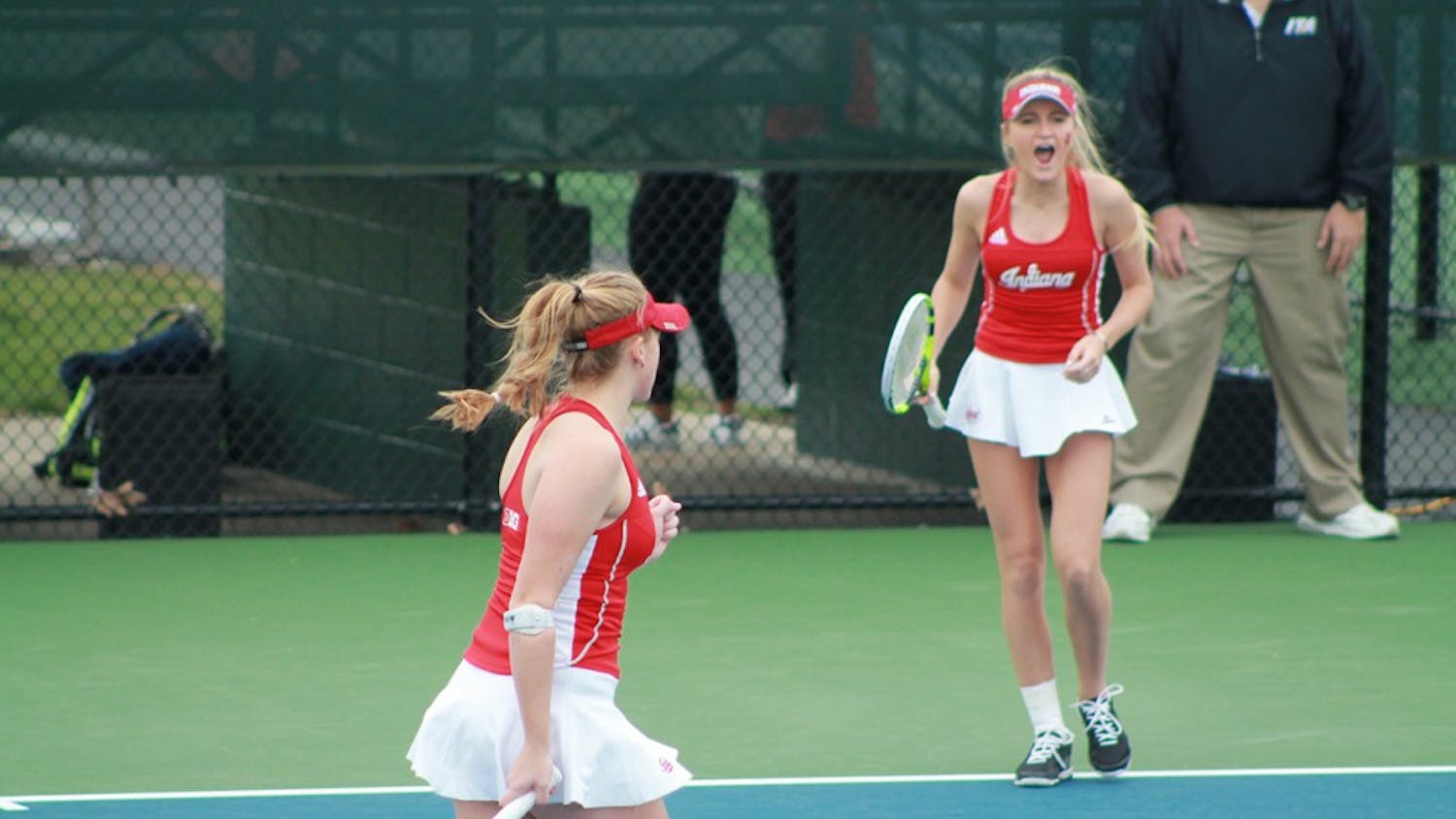 Partners Kim Schmider and Madison Appel celebrate after scoring a point in a doubles match Saturday morning. Schmider and Appel led 5-4 over No. 2 Michigan team when the match was stopped.&nbsp;