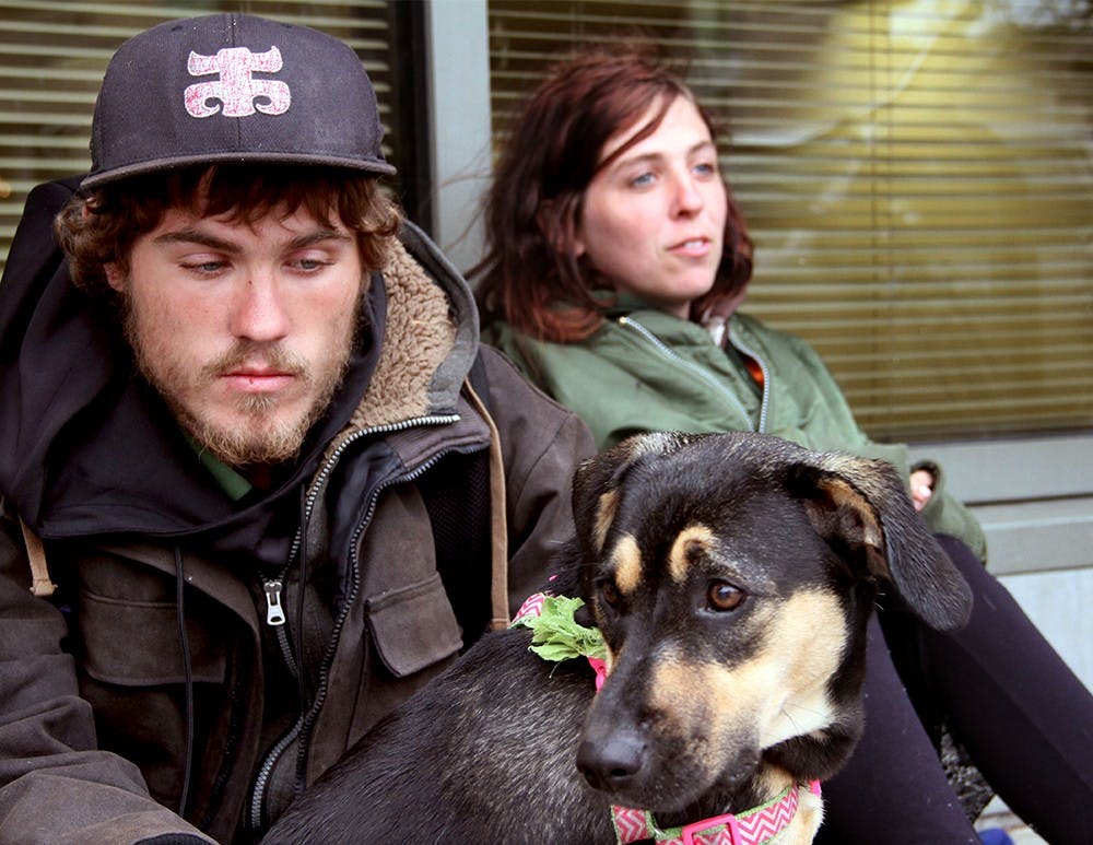 Kody Lydy, 20, and Ivy Andrews, 21, and their dog Roxie, take shelter from a storm Wednesday outside the Monroe County Public Library. Andrews is a month and a half pregnant. The couple currently live in a tent behind an apartment complex. 