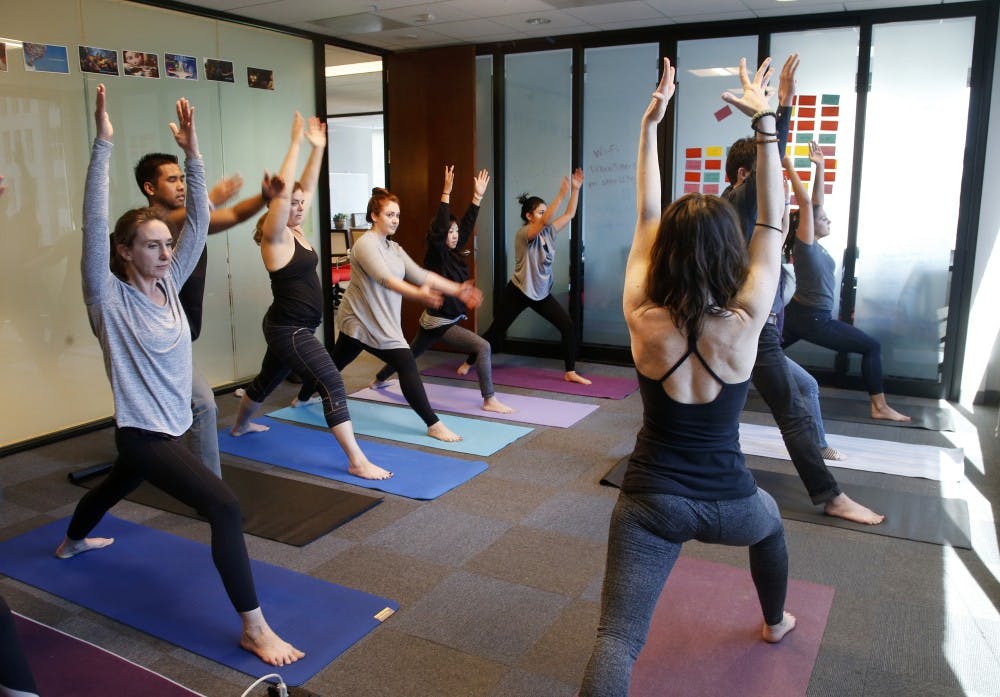 A group of people do yoga. The SRSC has yoga classes available free for students.