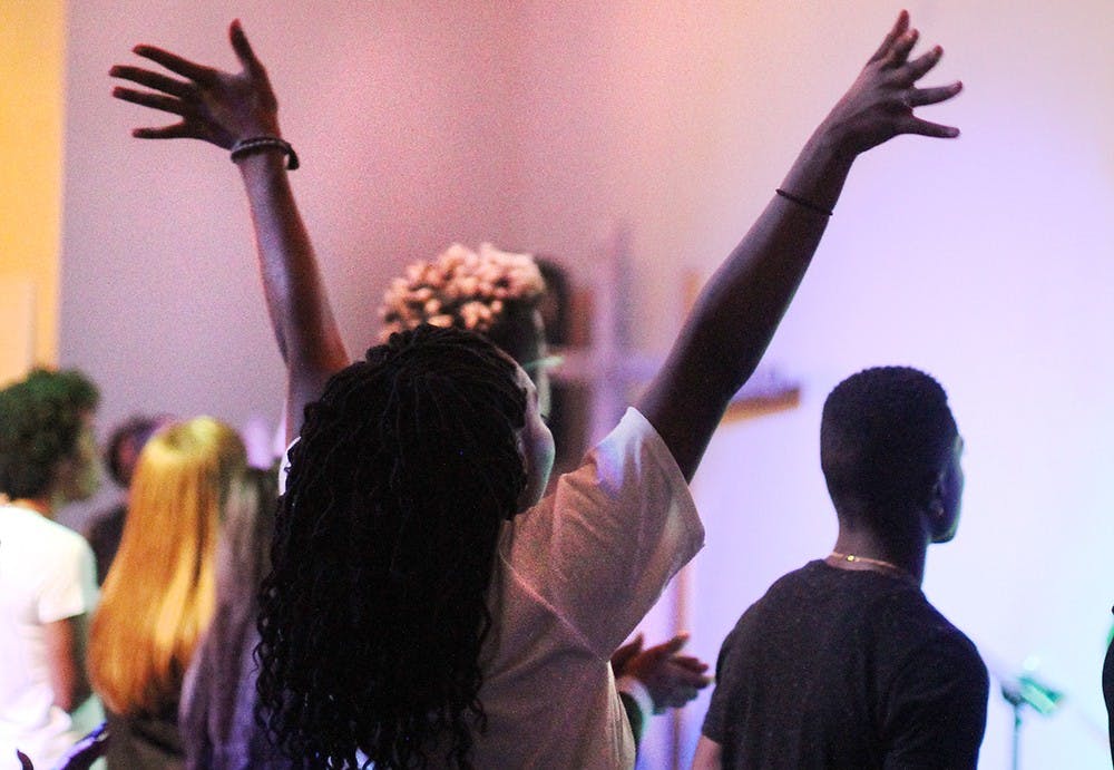 Senior Kennedy Coopwood raises her hands in praise during worship at City Church in Bloomington.