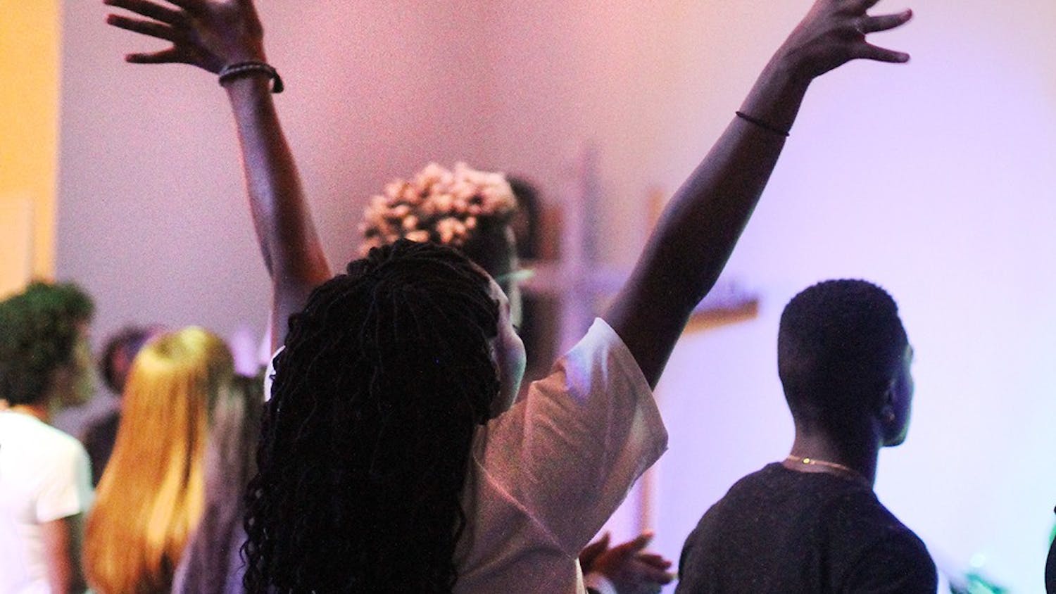 Senior Kennedy Coopwood raises her hands in praise during worship at City Church in Bloomington.
