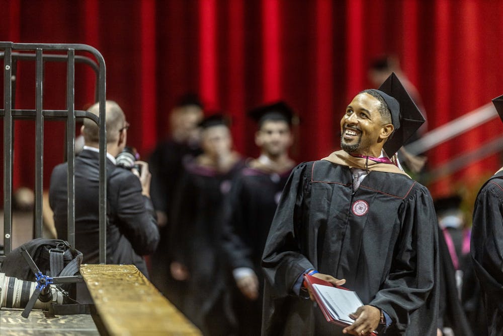 <p>A graduate smiles at the crowd while heading back to his seat after walking across the stage May 6, 2022, in Simon Skjodt Assembly Hall. The Indiana University Board of Trustees supported incorporating forensic science and school psychology degrees into various campuses.</p>