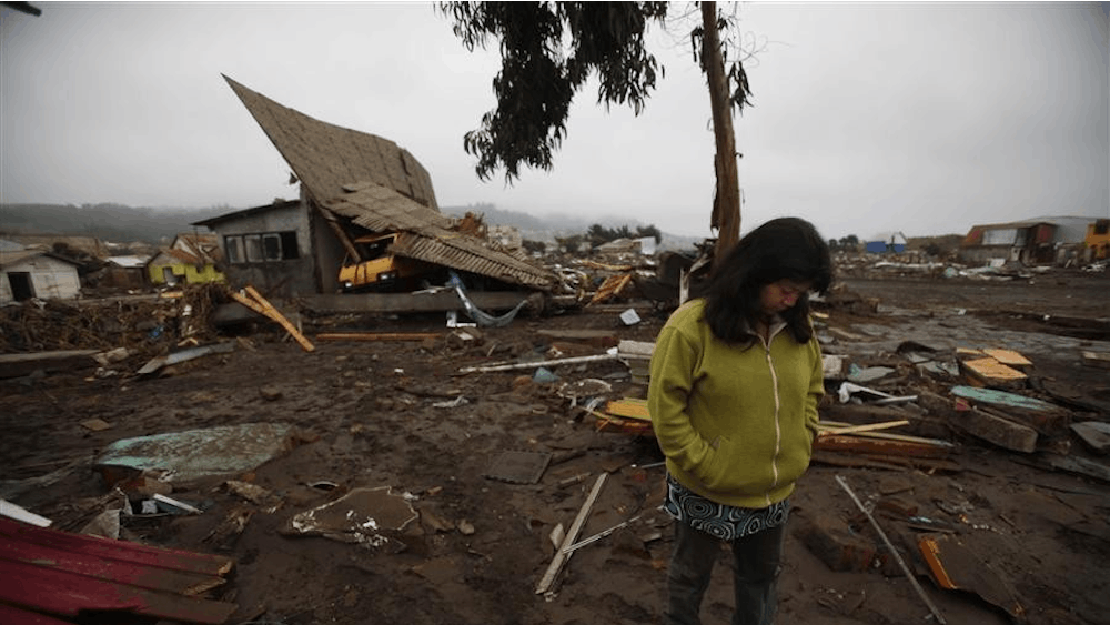 Rosa Neira, 36, stands in front of a damaged house after an earthquake in Pelluhue, some 322 kms, about 200 miles, southwest of Santiago, Sunday, Feb. 28, 2010. A 8.8-magnitude earthquake hit Chile early Saturday. 