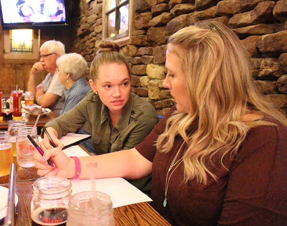 Lizzy Gentry and Samantha Geyer discuss answers at trivia night Thursday at Nick's English Hut. Proceeds from the trivia night benefit the Community Kitchen of Monroe County.