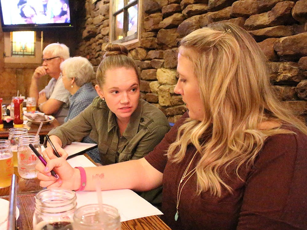 Lizzy Gentry and Samantha Geyer discuss answers at trivia night Thursday at Nick's English Hut. Proceeds from the trivia night benefit the Community Kitchen of Monroe County.