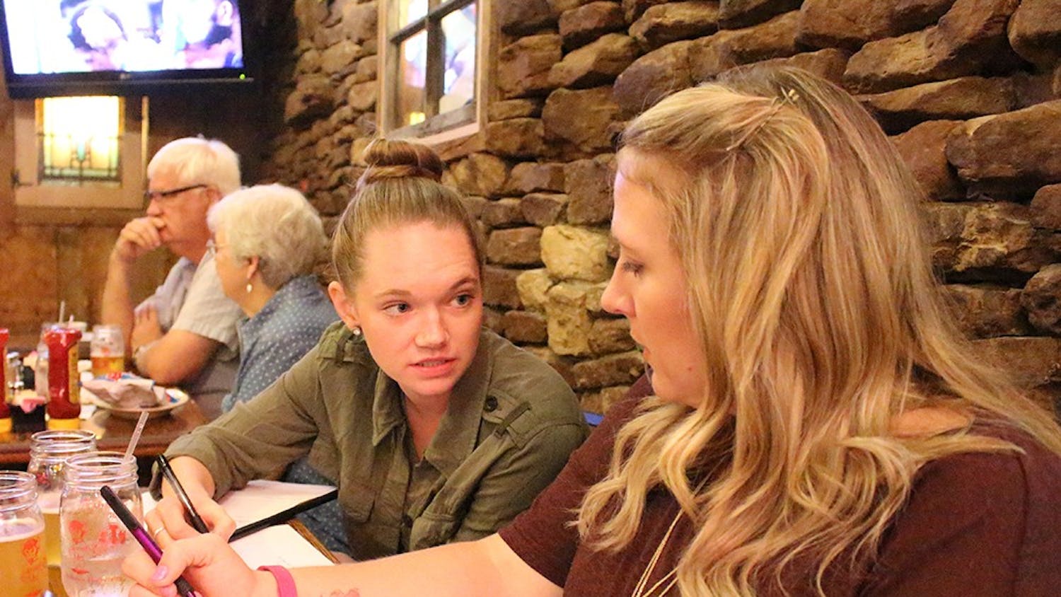Lizzy Gentry and Samantha Geyer discuss answers at trivia night Thursday at Nick's English Hut. Proceeds from the trivia night benefit the Community Kitchen of Monroe County.
