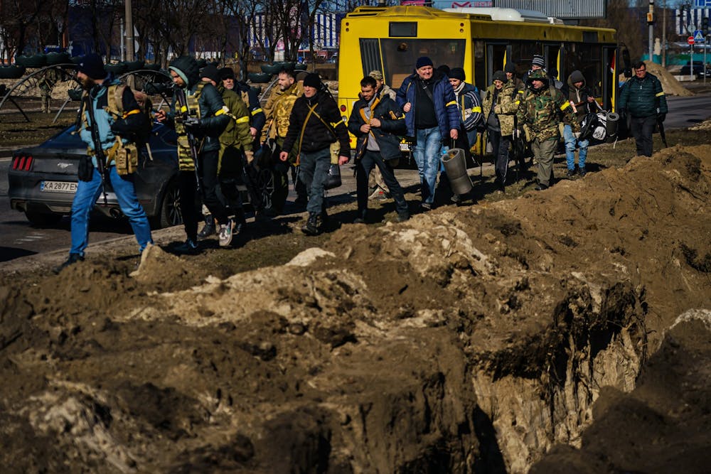 <p>Volunteers for Ukrainian Territorial Defense Units arrive and march past trenches dug to defend their positions against the incoming Russian invasion on Feb. 28, 2022, in Kyiv, Ukraine. The Ukrainian city of Kherson fell to Russian forces, Ukrainian officials said Wednesday.</p>