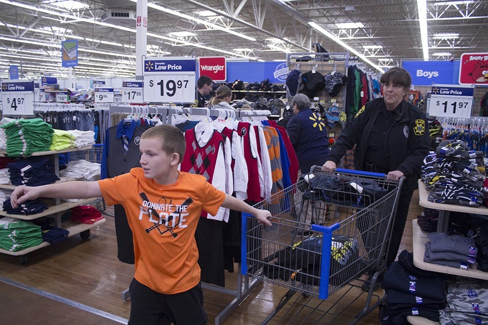 Nine-year-old Richard Freeman pulls his shopping cart behind him as IUPD officer Debbie Delay helps to push it during the Shop with Cop event at Walmart on Sunday morning.