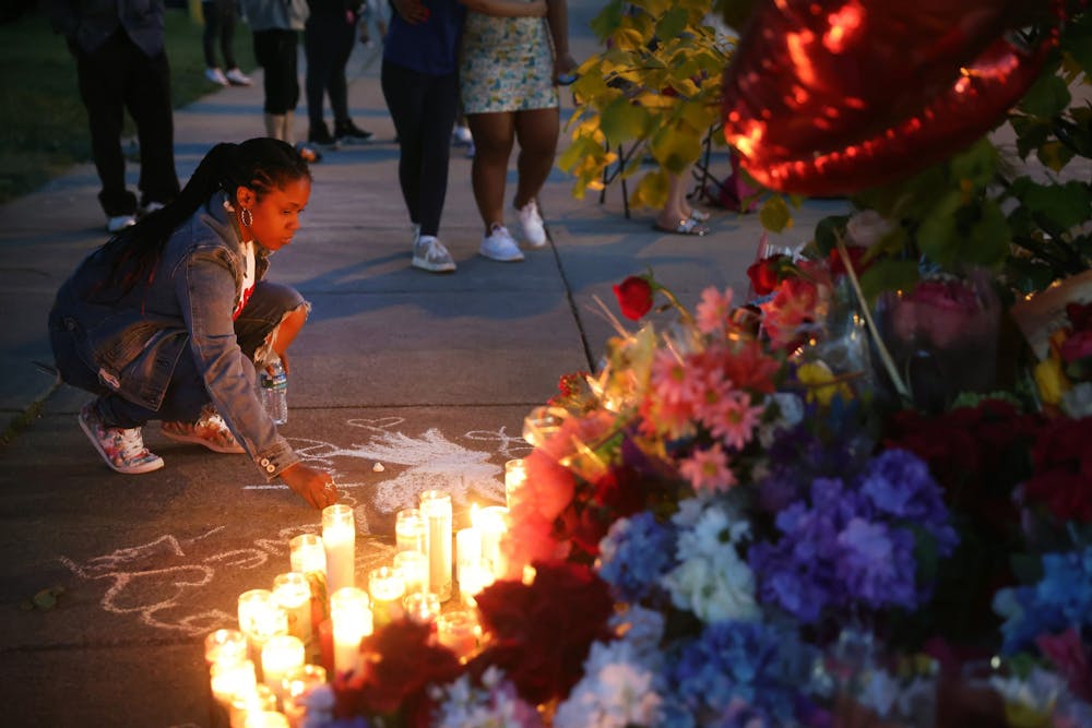 <p>A woman chalks a message at a makeshift memorial outside of Tops market on May 15, 2022, in Buffalo, New York. A gunman opened fire at the store, killing 10 people and wounding another three. </p>