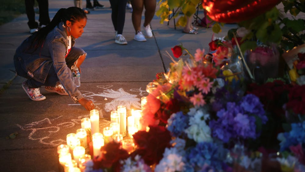 A woman chalks a message at a makeshift memorial outside of Tops market on May 15, 2022, in Buffalo, New York. A gunman opened fire at the store, killing 10 people and wounding another three. 