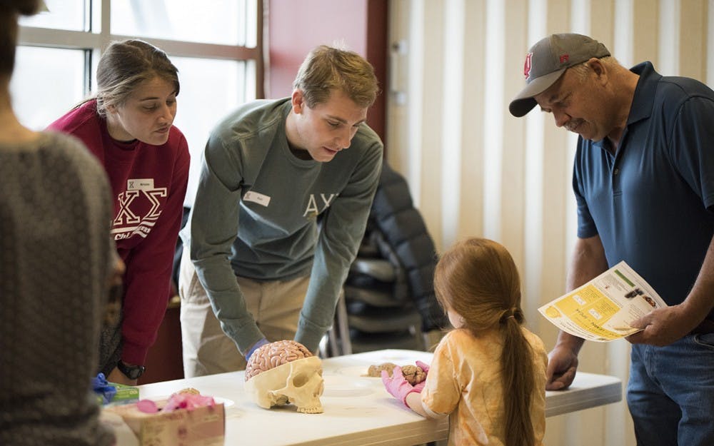 Kristen Swanson (left) and Petr Sliva (right) from Alpha Chi Sigma teach kids about sheep brains. The fraternity held a lab for kids at Wonderlab Monday morning where kids could extract DNA, make electricity and learn about anatomy. 