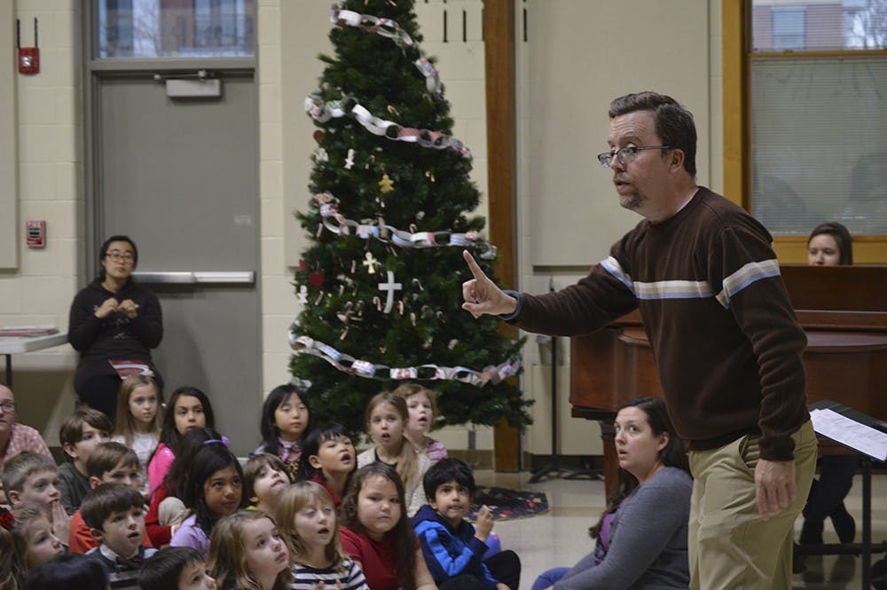 Etienne Lamb (left) and Story Bolton watch the IU Children's Choir director as they rehearse for the program's Winter Concert. The performance will feature a mixture of Christmas, Hanukkah and secular songs, and it begins at 1 p.m. Saturday at St. John the Apostle Church. 