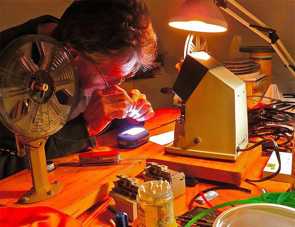 Joseph Bernard works at his workbench, Bernard is an experimental filmmaker and is giving a lecture at the IU Cinema, which will be followed by a screening of his short films.