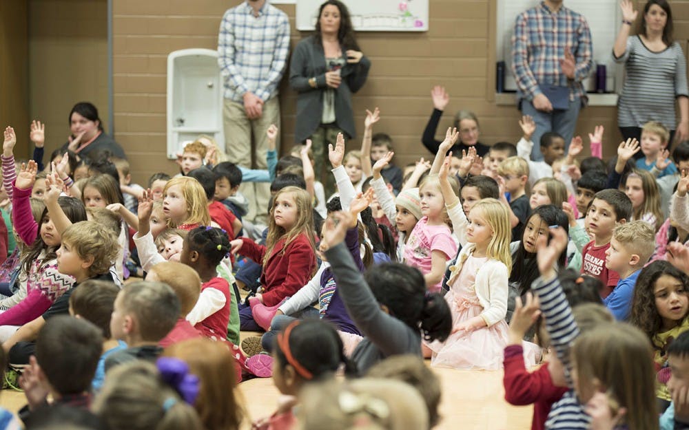 Students at Rogers Elementary raise their hands for the Martin Luther King Day celebration Thursday night. The students performed songs and honored community members for their service.