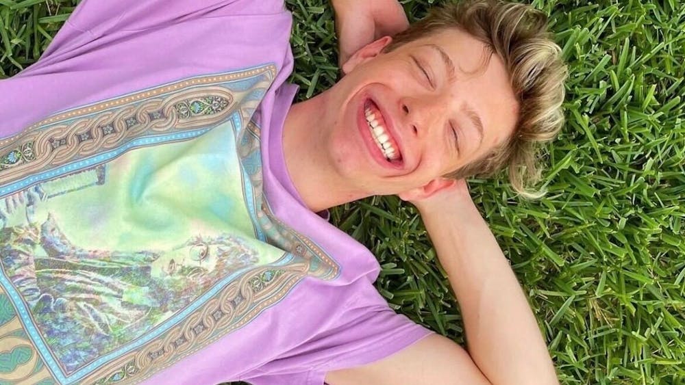 Nate Stratton is seen smiling, laying in the grass. He and his dad, Brad Stratton,  played pickleball this past summer often. “It’s just those little moments,” he said. “I’ve been going to sleep every night thinking about him dancing around the pickleball court with a big smile on his face because he beat me.”