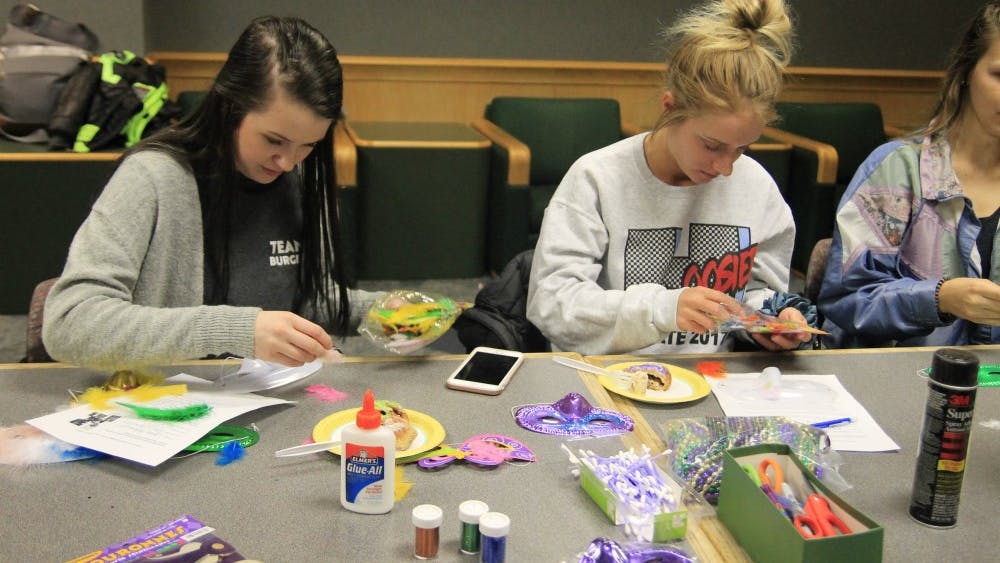 Freshman roommates Lauren VanderReyden and Rylea James make masks as a Mardi Gras tradition. The French Club and classes celebrated Mardi Gras on Tuesday, Feb. 13, in Ballantine Hall.