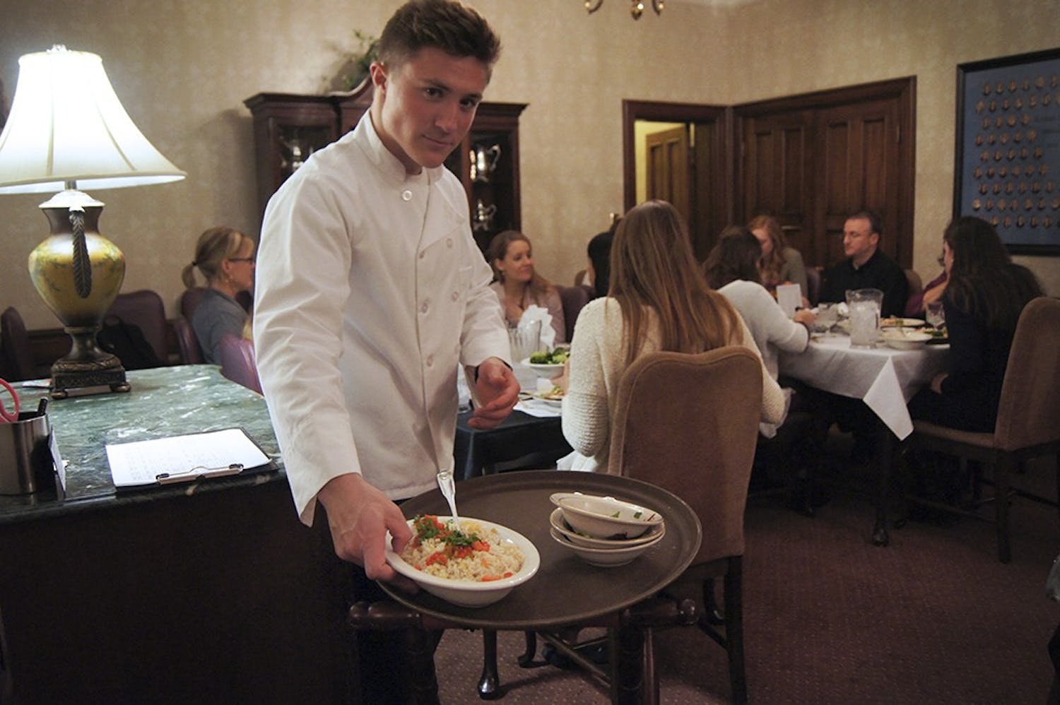 Evans Scholar Jack Conway helps serve formal dinner at the Kappa Alpha Theta house on Wednesday. Evans Scholars work as kitchen staff at a sorority house of their choice to supplement for their house not having a kitchen. This opportunity provides the Scholars with meals, and a paid job as well. 