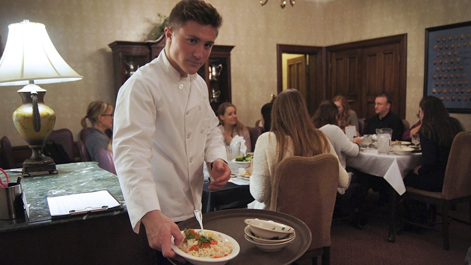 Evans Scholar Jack Conway helps serve formal dinner at the Kappa Alpha Theta house on Wednesday. Evans Scholars work as kitchen staff at a sorority house of their choice to supplement for their house not having a kitchen. This opportunity provides the Scholars with meals, and a paid job as well. 
