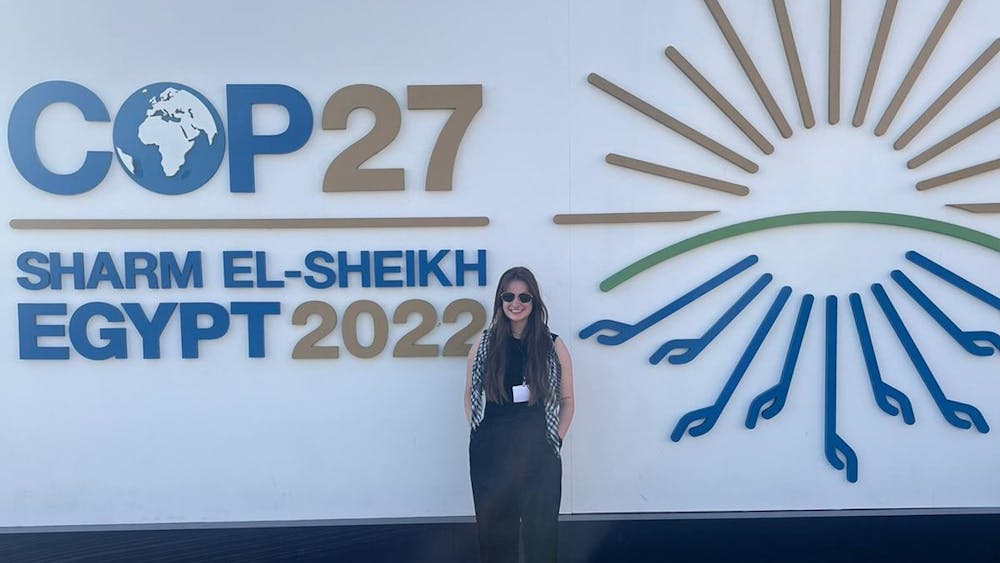 IU student Abby Potter stands against a sign for the 27th Conference of the Parties in Sharm El-Sheikh, Egypt. IU students attended the summit as part of Professor Jessica O’Reilly’s international climate government course.