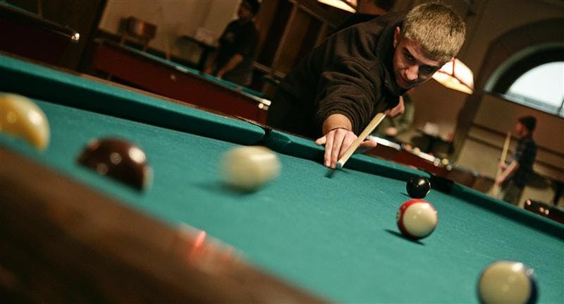 Junior Alex Rittenhouse makes a shot Monday evening in the Indiana Memorial Union Back Alley . The IU Pool Club meets Monday from 7 to 9 p.m. in the IMU, and has many members of various skill levels.