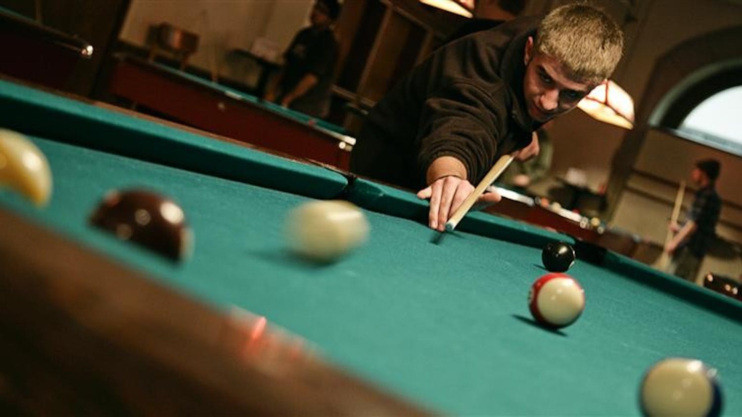 Junior Alex Rittenhouse makes a shot Monday evening in the Indiana Memorial Union Back Alley . The IU Pool Club meets Monday from 7 to 9 p.m. in the IMU, and has many members of various skill levels.