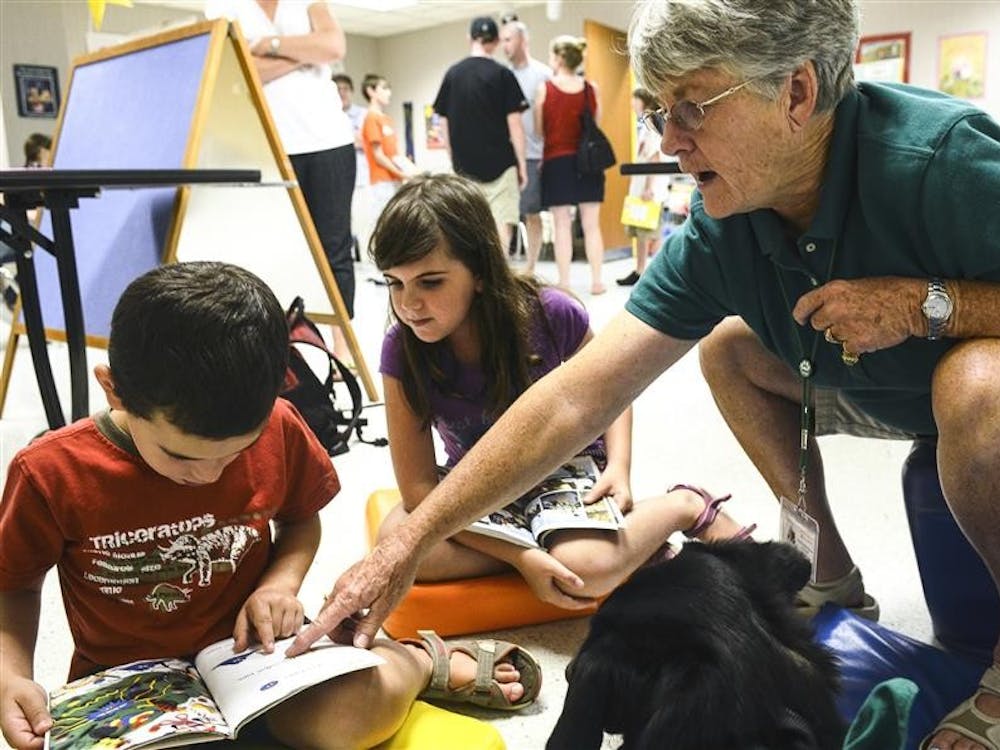 Itamar and Stav Katz practice reading outloud to Rusell the therapy dog as volunteer Charlotte Blackketter assists them on Saturday at the Monroe County Public Library. Blackketter and Rusell are a part of the volunteer program Pet Partners through the Monroe County Humane Association.