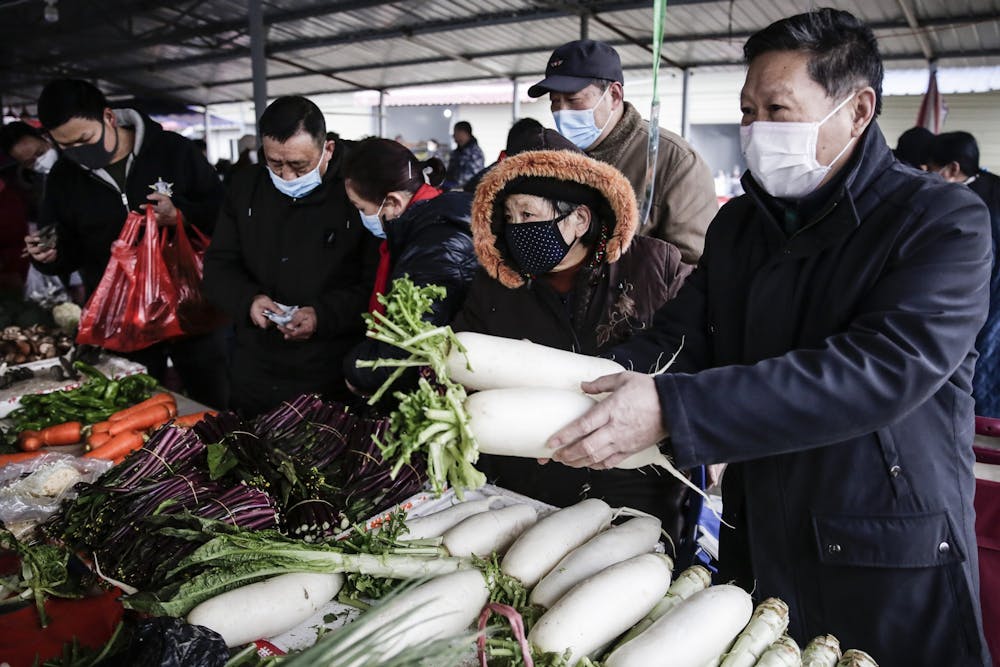<p>Chinese residents wear masks to buy vegetables Jan. 23 at a market in Wuhan, Hubei.</p>