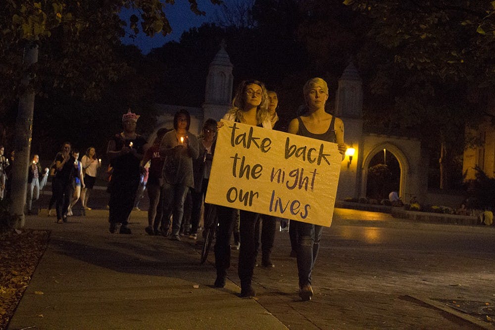 Alum Shelby Everett and IU senior Savannah Lynch lead a silent march for Take Back the Night on Thursday night past the Sample Gates. The march went from Dunn Meadow to Courthouse Square and was used to raise awareness of abuse and assault.