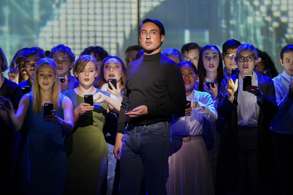 <p>A mob of smartphone users grows behind Steve Jobs, portrayed by Edward Cleary, as the cult following of Apple products is depicted during the “(R)evolution of Steve Jobs” rehearsal Sept. 11 in the Musical Arts Center. The opera tells the story of the life and death of Apple co-founder Steve Jobs.</p>
