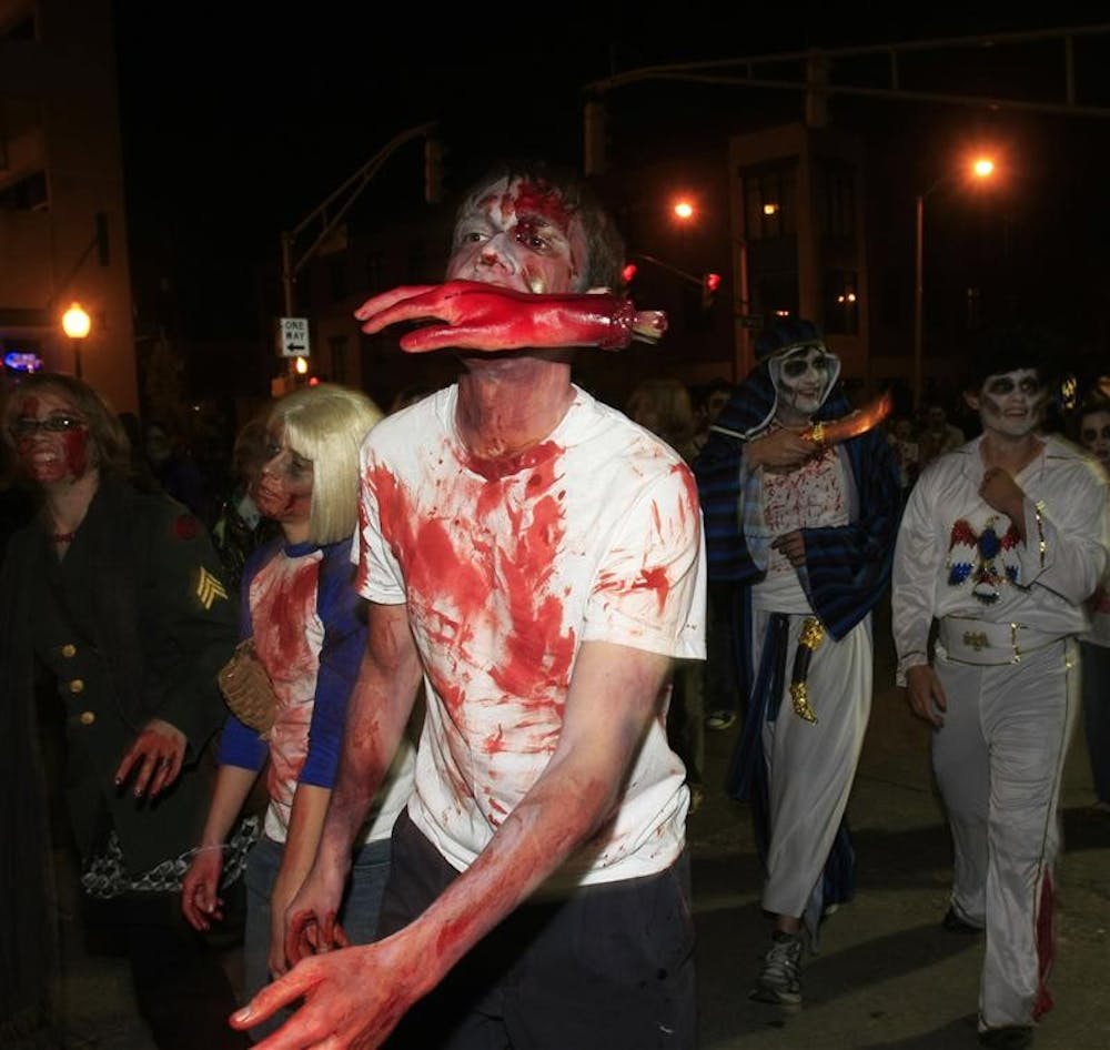 Zombies lurch down Walnut and Seventh streets Friday night in anticipation for Halloween. The parade drew about 100, many dressed in full zombie attire. The parade was cut short after police intercepted the crowd.
