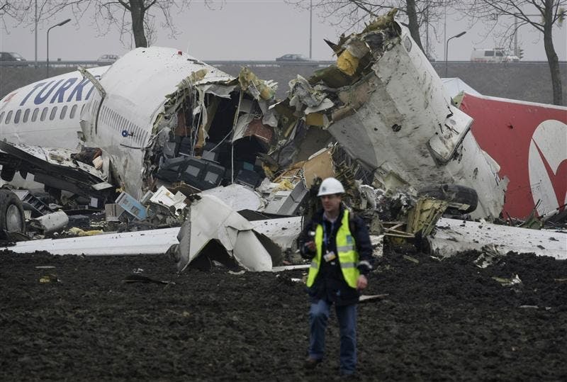 A Forensic expert is seen near the wreckage of a Turkish Airlines plane at Amsterdam's Schiphol Airport Wednesday. The plane with 134 people aboard slammed into a field while attempting to land and broke into three pieces. Nine people died in the crash.