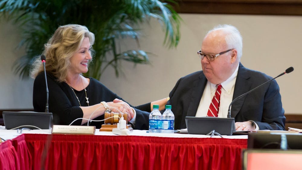 Trustees MaryEllen Bishop and James Morris shake hands July 2019 at an IU Board of Trustees meeting. Morris retired from his position after more than two decades of service.
