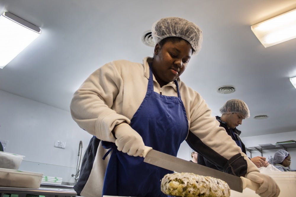 <p>Chazney Jones, a member of the Minority Association of Pre-Medical Students, slices broccoli Feb. 20 at Hoosier Hills Food Bank. Jones said the best part about volunteering is knowing she is helping out her community.</p>