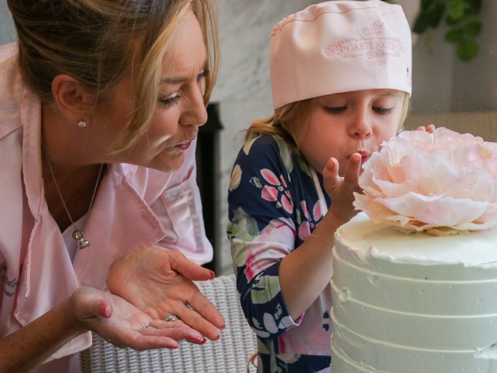 Roslyn and Gwendolyn Rogers make a wish on Rosyln&#x27;s cake by blowing glitter on it May 12 in the Broad Ripple location of the Cake Bake Shop. After the cake was fully done Roslyn was able to brush glitter on it, a Cake Bake Shop tradition. 